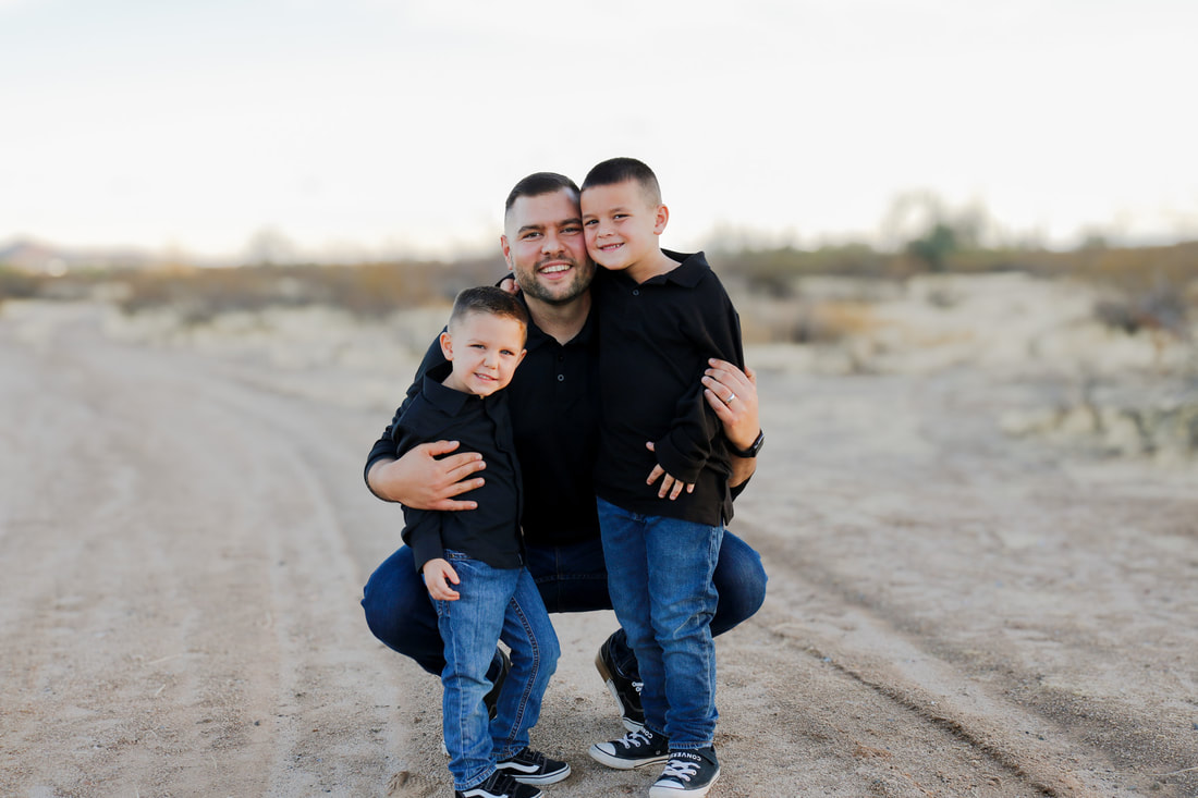 Father and sons crouched together, desert